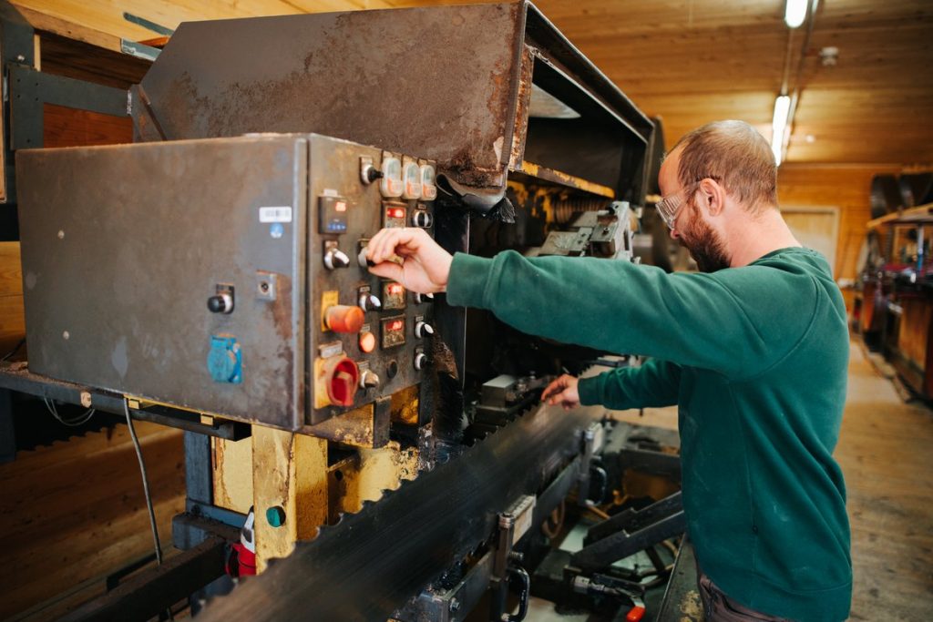 Mitarbeiter bedient das Steuerpult einer Sägewerksmaschine