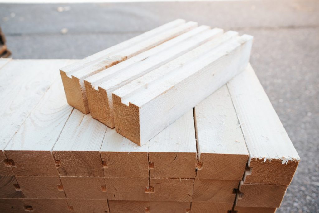Mit Gurten gesicherte Holzbalken mit sichtbaren Hirnholzenden